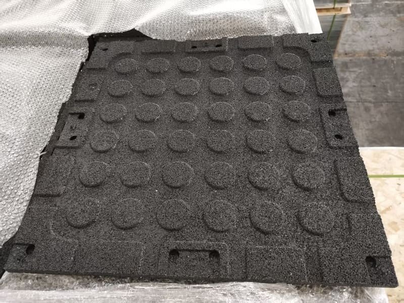 Mann reinigt Gummifußboden in der Turnhalle mit Bürste